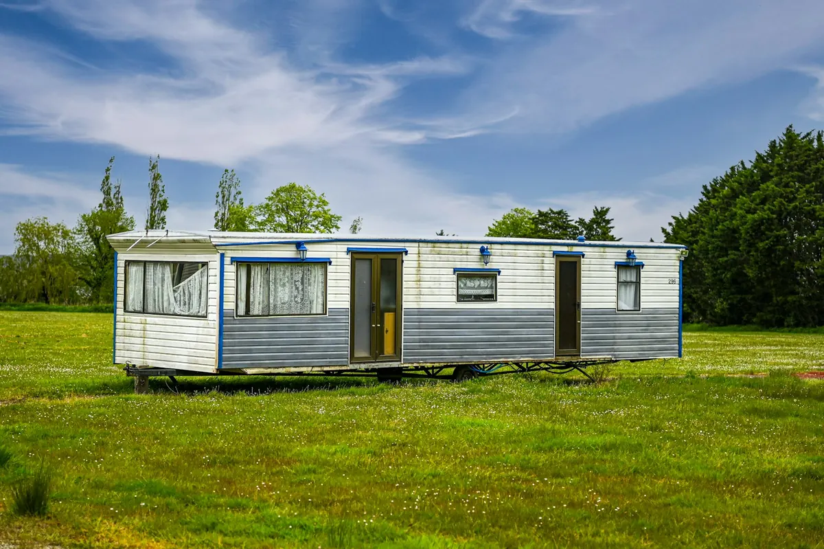 Single wide mobile home standing in a grassy field